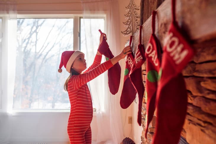 Girl hanging Christmas stockings on a fireplace