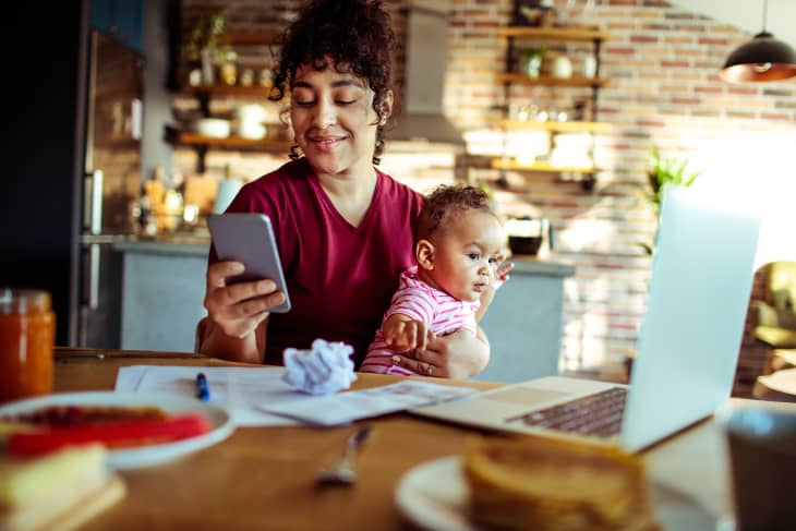 Close up of a mother using a phone with her daughter while having breakfast and doing bills
