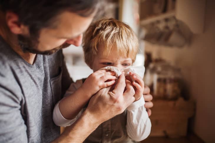 father taking care of his sick toddler son. Helping him blow his nose