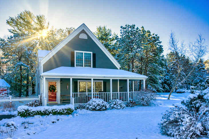 Morning sun rises behind a single family home on Cape Cod decorated for Christmas after a light overnight snowfall