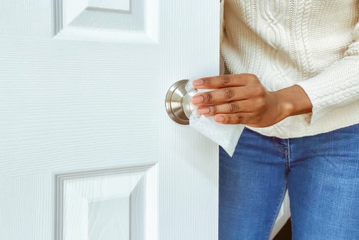 Woman Cleans Doorknob with disinfectant wipe