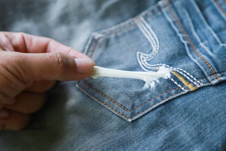 Hand Removing Chewing Gum Stuck On Jeans