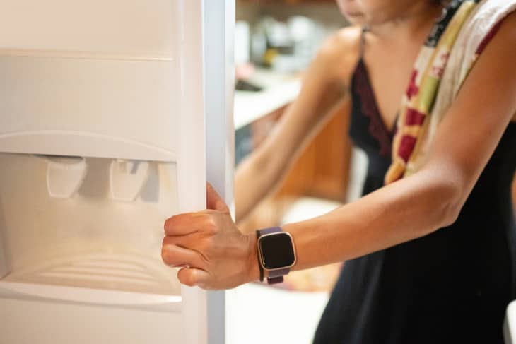 Arm of Young Woman Opening up Refrigerator Door at Home.