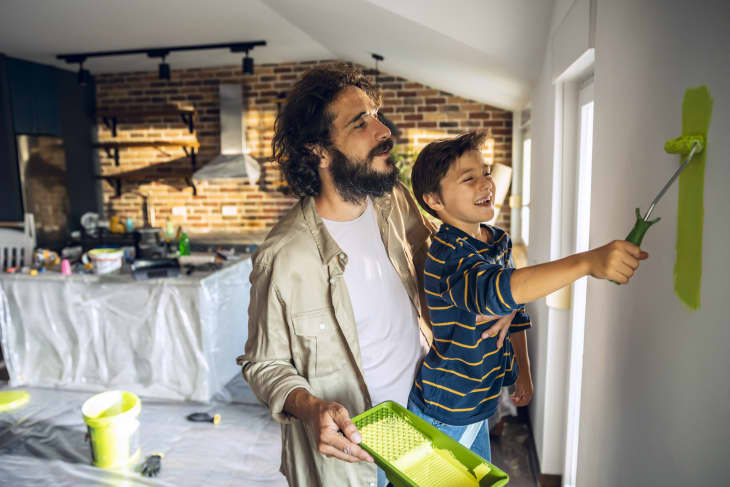 Close up of a father and son painting the walls of their home.