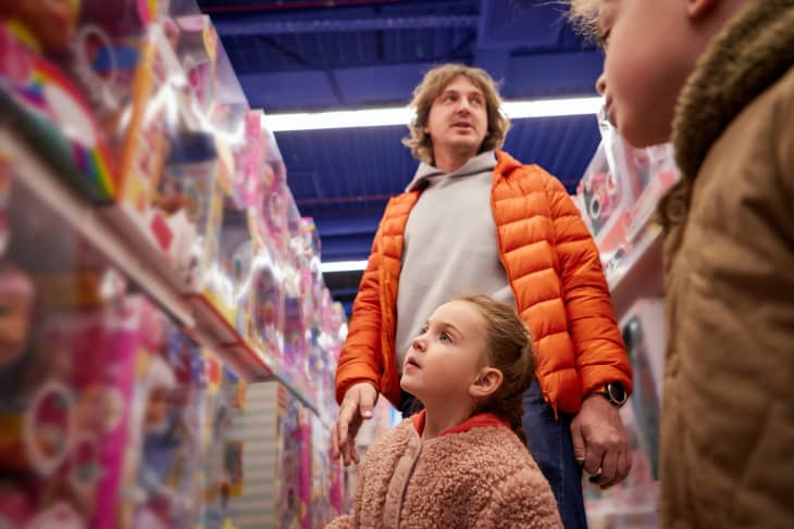 Dad with a small child at the rows of toys in a children's store