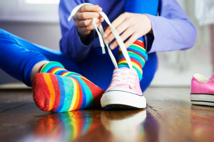 Young child tying shoe laces with colourful socks