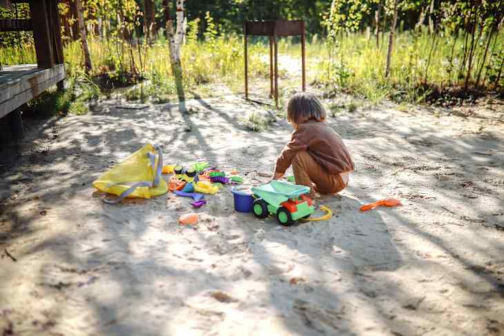 Nature's Playground: Toddler Boy Immerses in Sand Play by the Forest House