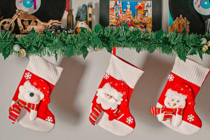 Three festive Christmas stockings hang from a garland, featuring a polar bear, Santa, and a snowman design.