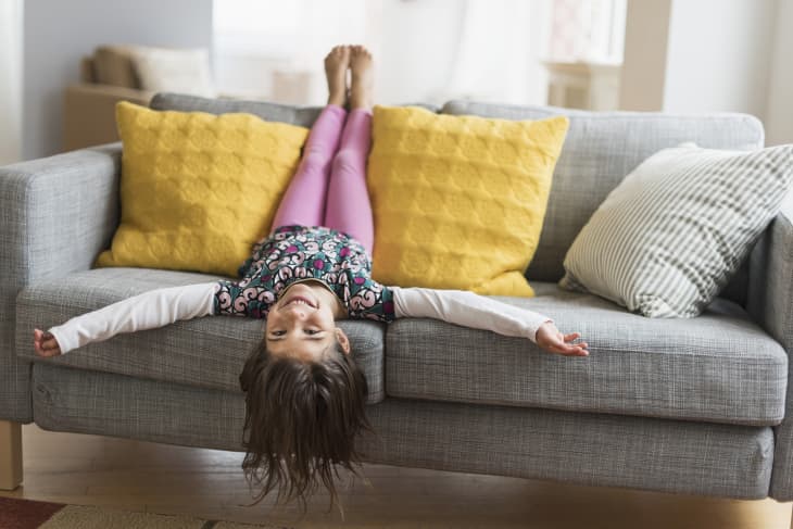 Girl lying on gray sofa with yellow pillows sofa upside down