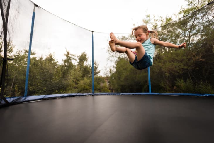Little girl enjoying as she jumps on trampoline bed