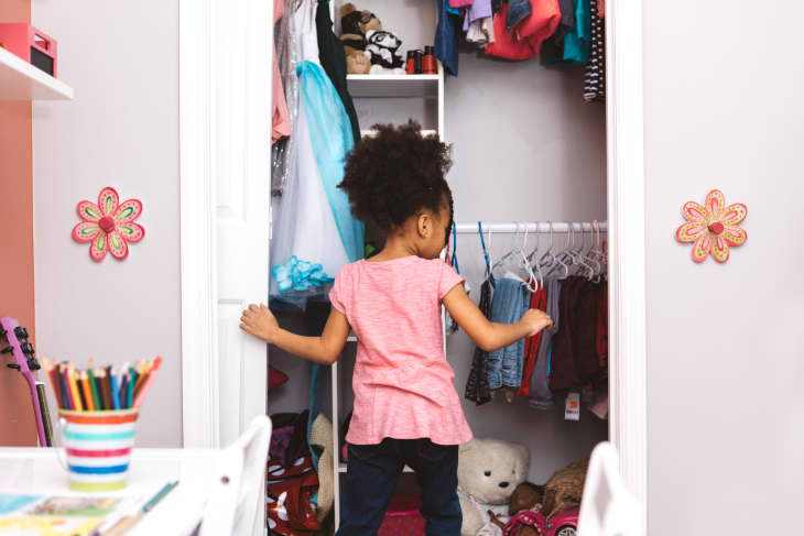 Little girl looking at clothes in her closet