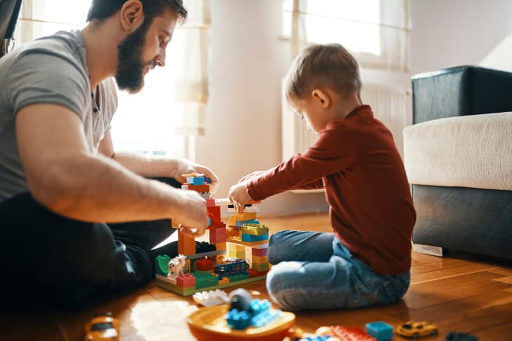 Father and son sitting on the floor playing together with building bricks