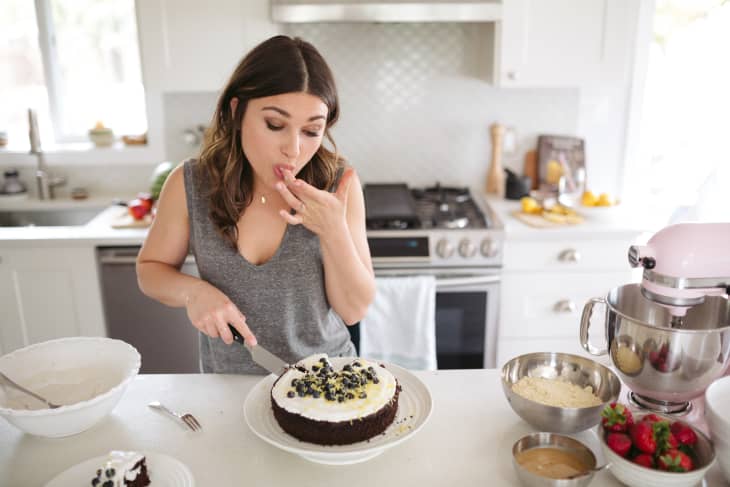 Woman in her kitchen cutting a slice of homemade cake