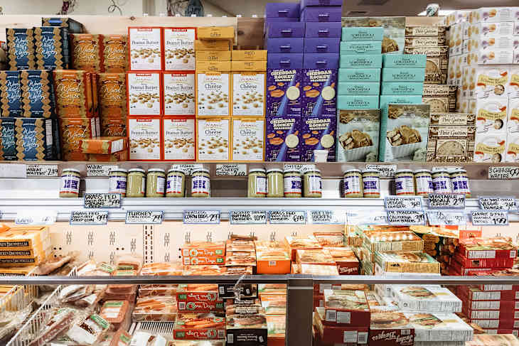 various cheeses and meats in a cooler in a store