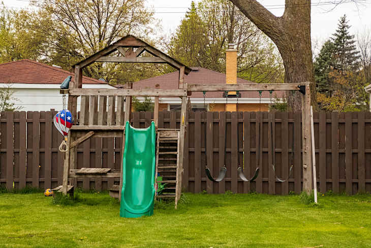Swing set in backyard during spring season with lush grassy lawn