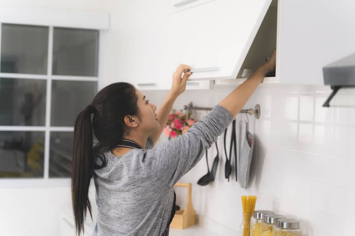 woman reaching into kitchen cabinet