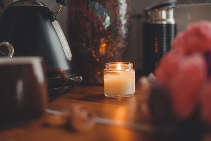 Cozy Christmas decor: burning candle on a wooden table top with garlands and decorations. Soft focus and beautiful color grading. New Year's Holidays.
