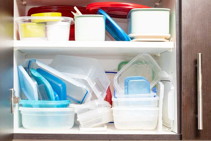 kitchen cabinet full of plastic food containers arranged in a haphazard manner