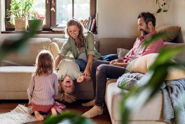Portrait of young family at home. Pregnant mother with her children and husband in living room.