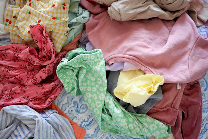 Clothes piled on a bed after laundry day in natural light