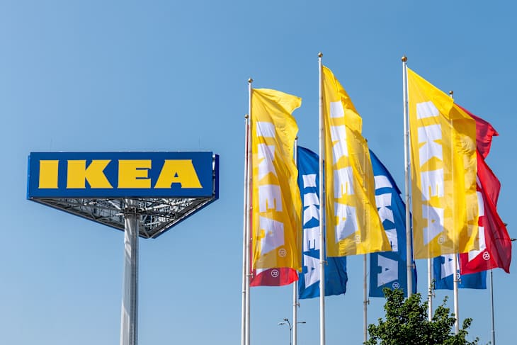 Bratislava, Slovakia - 06102025: IKEA logo and flags against a blue sky in Bratislava, Slovakia. Brand colors yellow and blue.