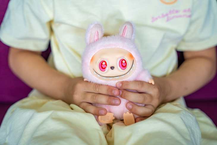 Budva, Montenegro - June 12, 2025: Close-up of pink Dada figure from Pop Mart LaBubu collection in child hands. Focus on popular collectible toy and emotional connection through play.