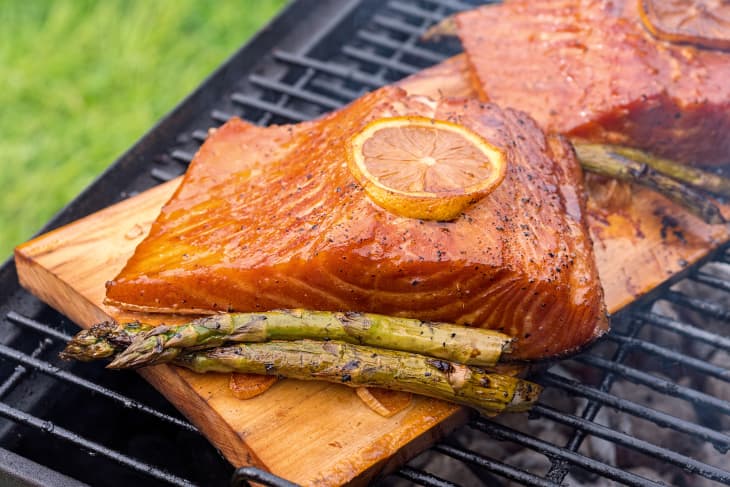 cedar plank salmon with lemon cooking on grill