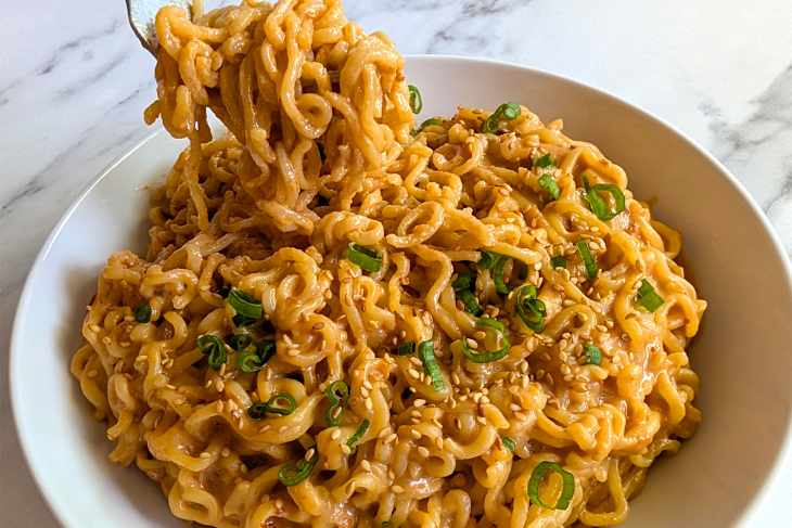 Someone taking forkful of peanut butter ramen.
