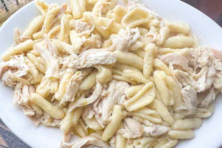Cavatappi pasta mixed with shredded chicken on a platter.