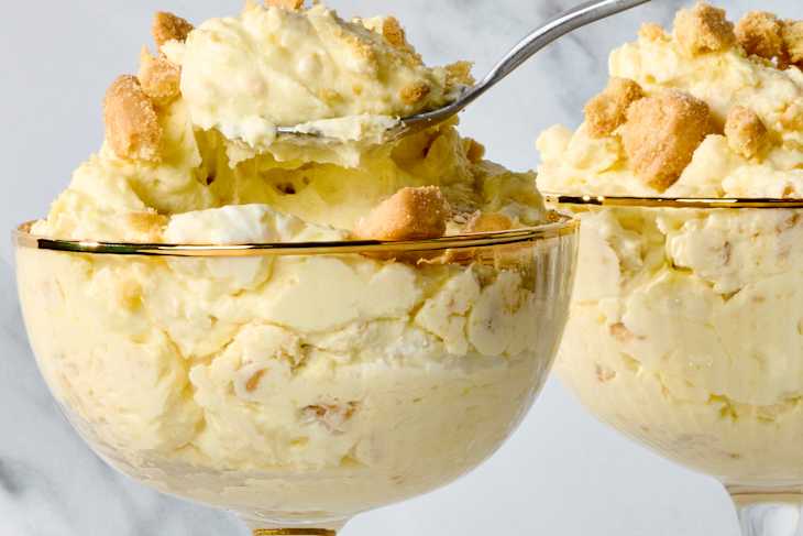 lemon fluff in glass bowls topped with crumbled cookies, served with a spoon.