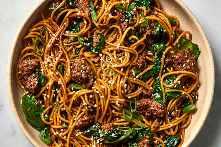 overhead shot of sesame noodles with ground beef and spinach in a bowl