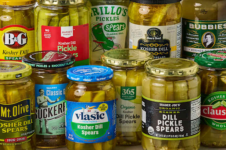 Various jars of kosher dill pickle spears from different brands, showcasing a variety of labels and colors.