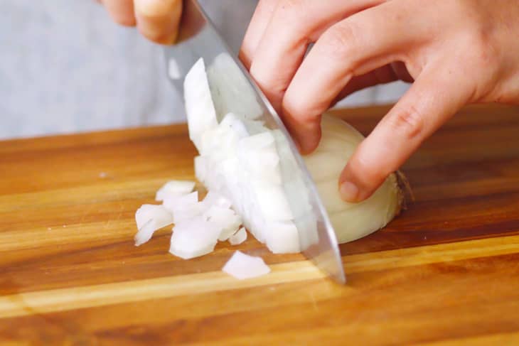 close up of hands dicing a white onion