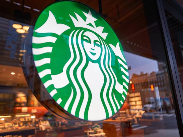 Starbucks logo on a glass window with a view of the store interior and street outside.