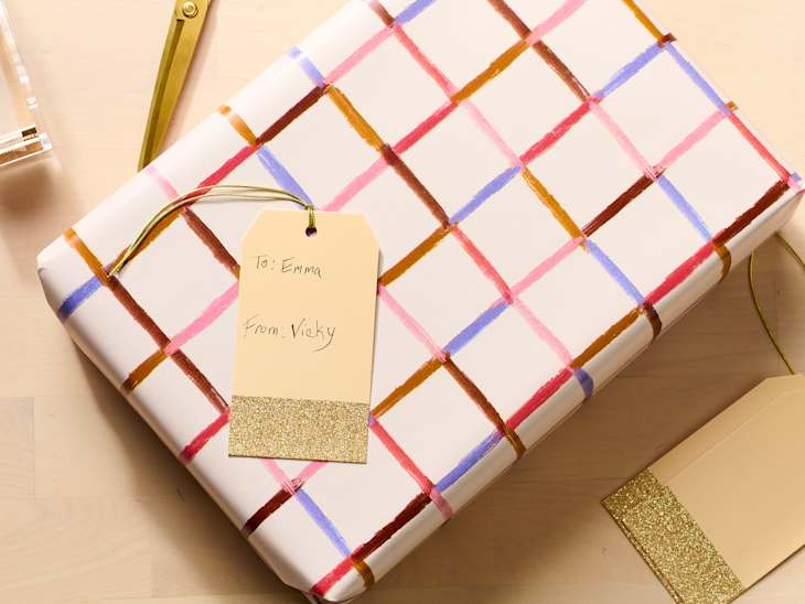 Gift wrapped in white paper with colorful grid patterns, featuring a tag that reads "To: Emma, From: Vicky."