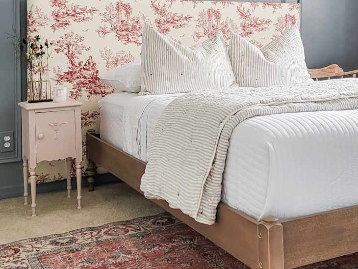 Bed with toile fabric headboard and slate blue wall behind