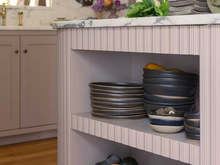 Dish ware stored in open shelving below kitchen island.