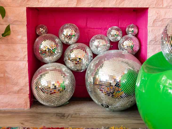 Disco balls filling pink painted fireplace.
