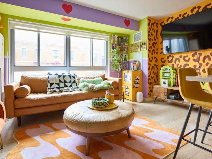 Colorful living room featuring a tan leather sofa, round coffee table, and vibrant decor with animal print walls.