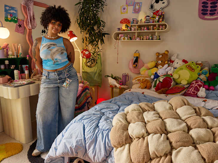 Student standing in dorm room that has lots of stuffed animals.