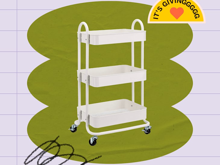 White three-tier rolling utility cart with metal frame and deep trays, set against a graphic green and lavender background with a sticker reading "It’s Givinggggg" and a heart emoji.