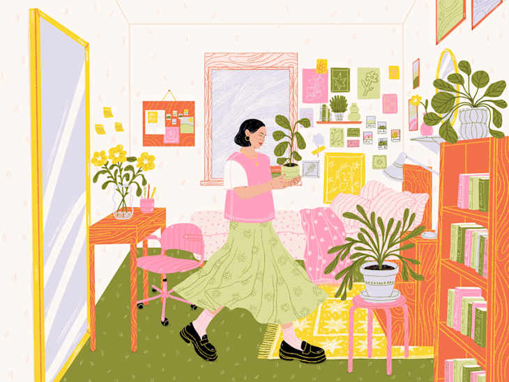 A woman in a pink top and green skirt holds a plant in a colorful, plant-filled room with a cozy sofa and desk.