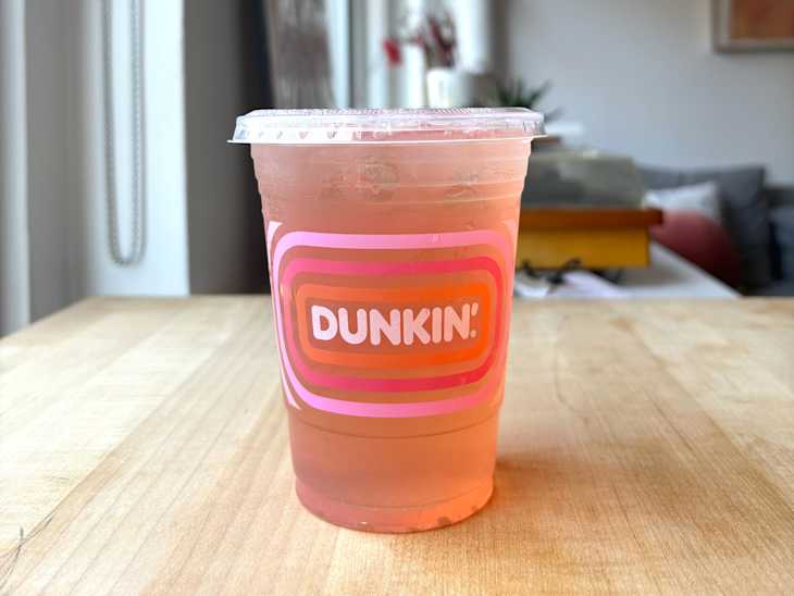 Dunkin' Pink Pineapple Refresher drink on table in front of window