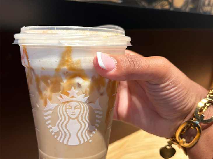 Someone holding Starbucks Iced Pecan Sticky Bun Latte.
