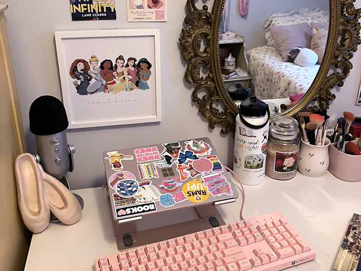 gallery wall, pink keyboard, computer, computer stickers, princess pop art, ornate gold oval mirror, ballet slippers, fuzzy chair, candles, water bottle