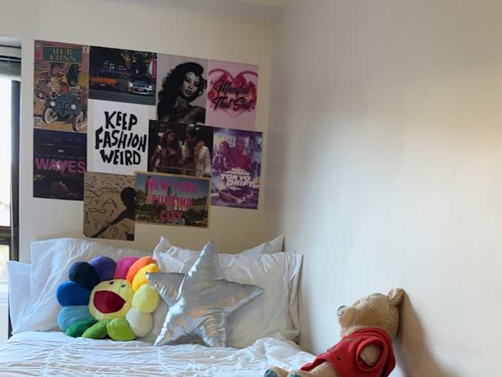 Bed in white dorm room with colorful art above