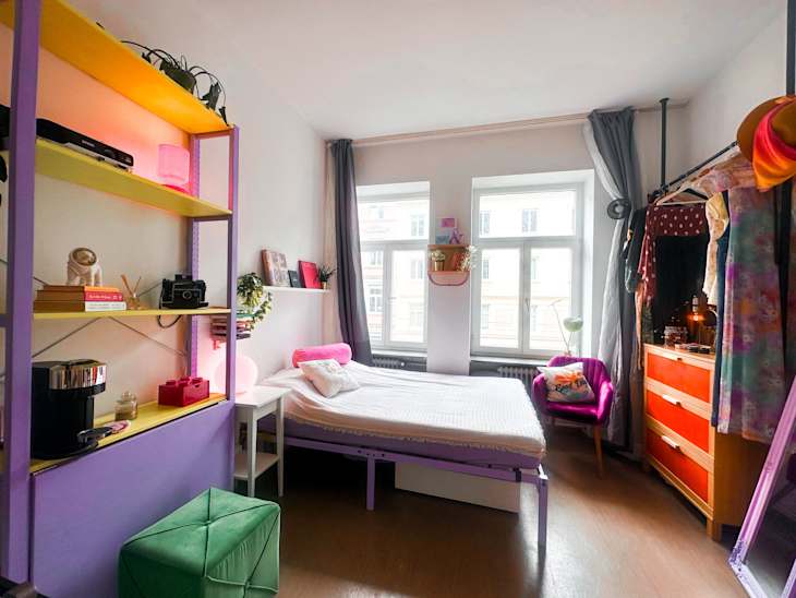 bed, exposed closet, and purple coffee station with floor to ceiling curtains