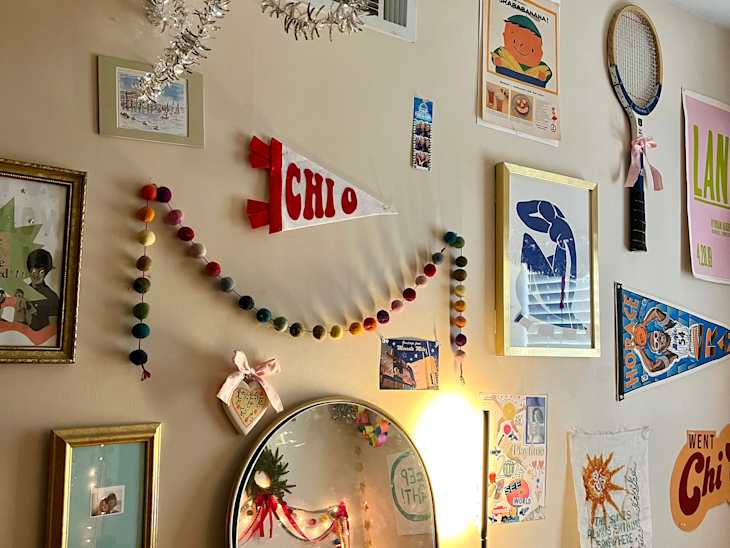 Colorful wall decor featuring a mirror, framed art, and a pennant, with a variety of personal items on a dresser.