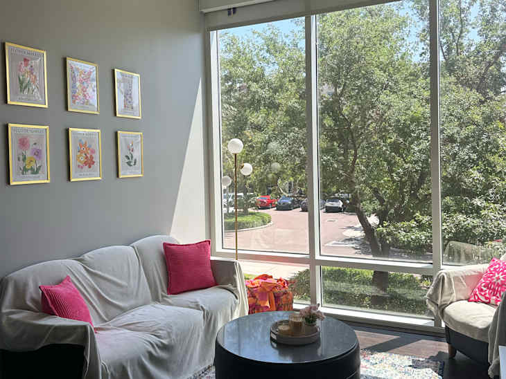 Framed art prints on wall above fabric draped living room sofa.