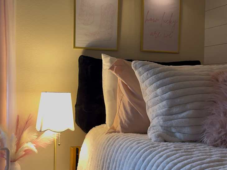 Framed artwork above neatly made bed in college dorm room.